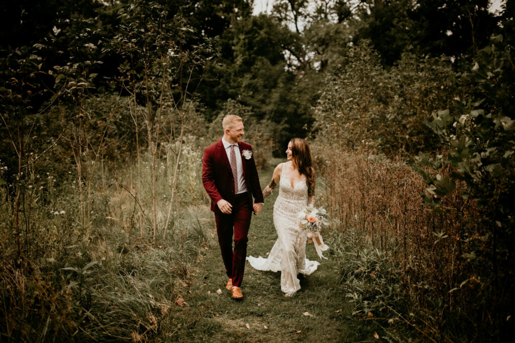 Newly married couple walks through a field