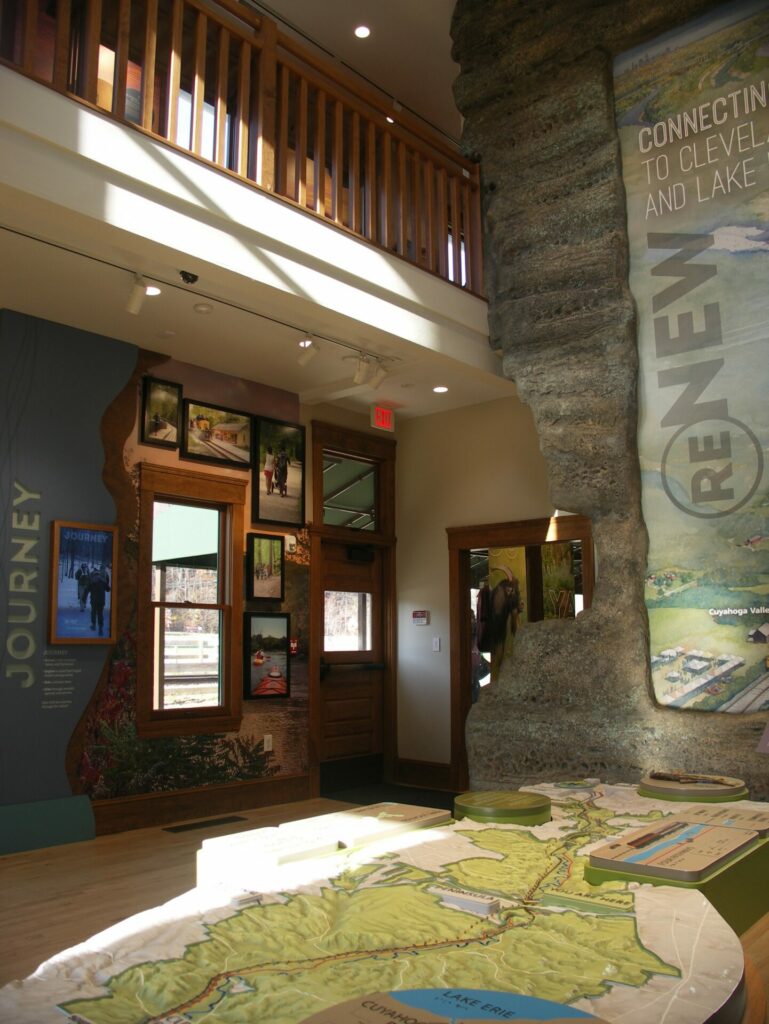 A tabletop relief map of Cuyahoga Valley National Park is opposite an informational wall with screens displaying photographs of the park.