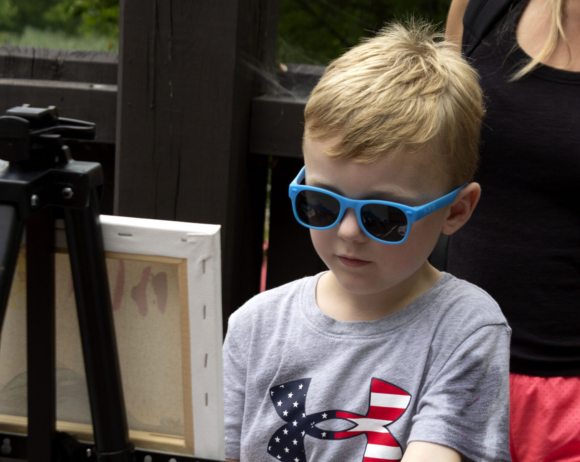 Boy wearing sunlgasses painting.