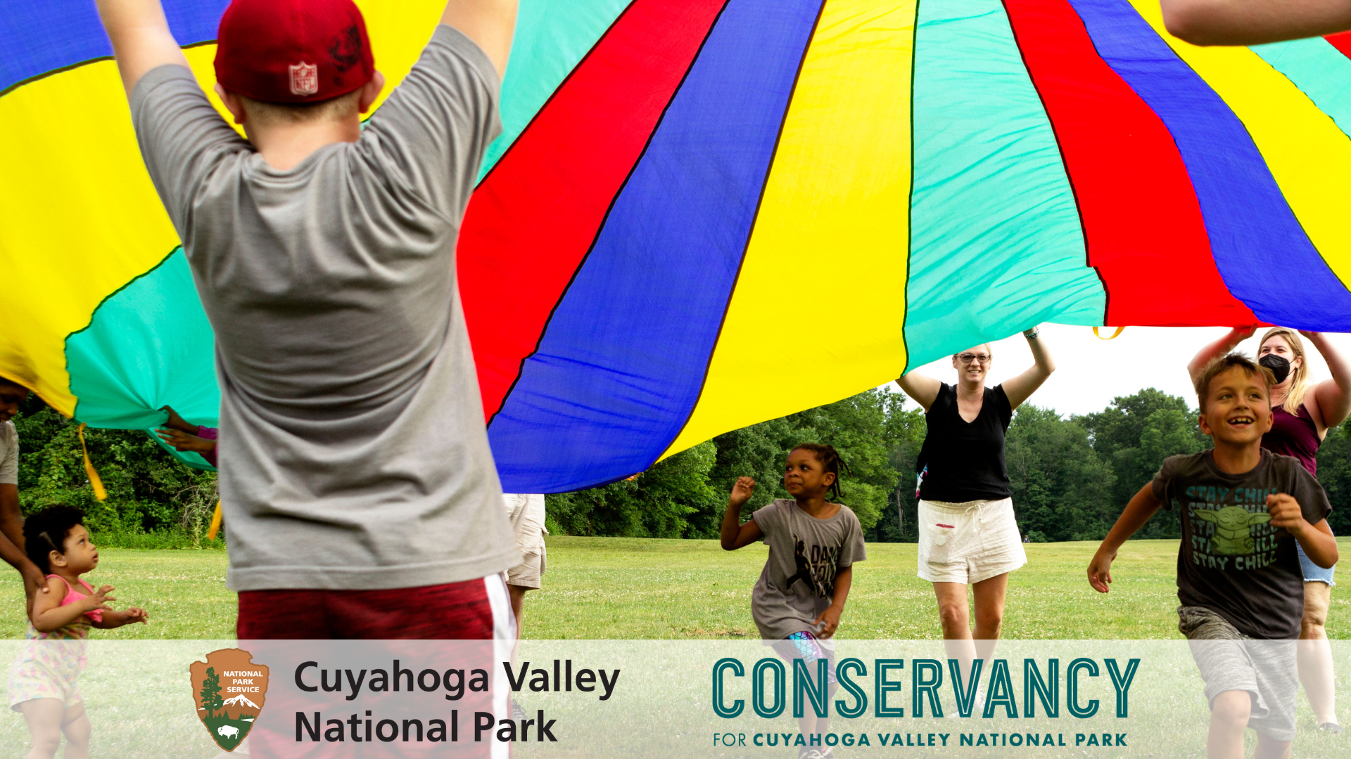 Children playing in field with a parachute.