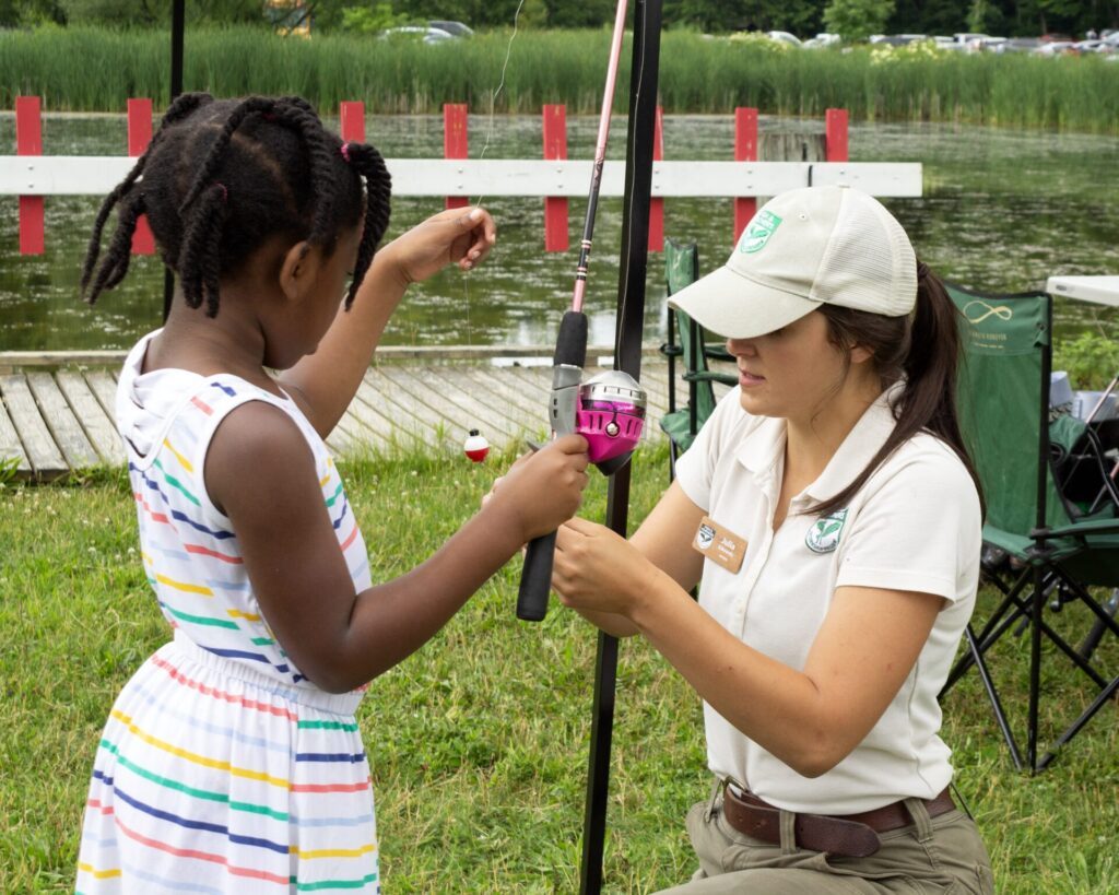 Women helping child with fishing pole at Family Fun Day.
