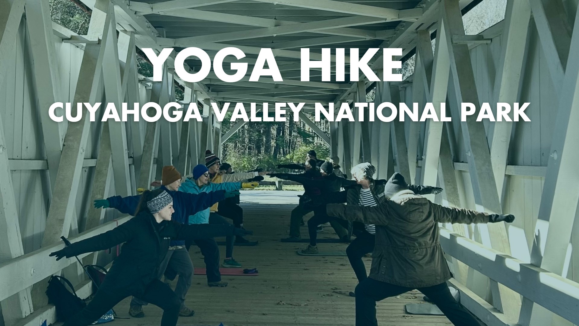 Group practicing yoga pose under covered bridge.