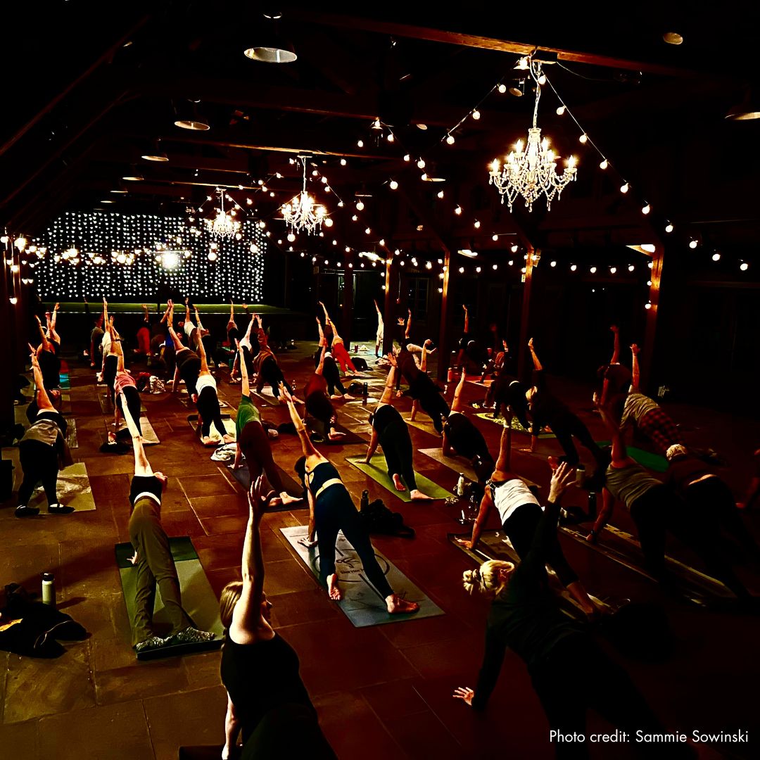 A photo of a large group of people doing yoga indoors in a rustic lodge in Cuyahoga Valley National Park.