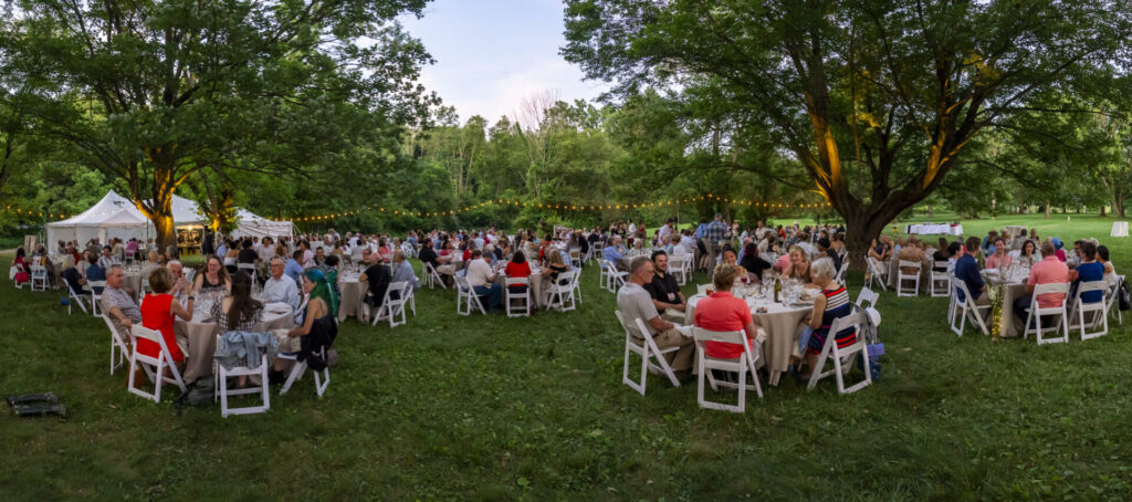 Attendees sit at tables al fresco under string lights