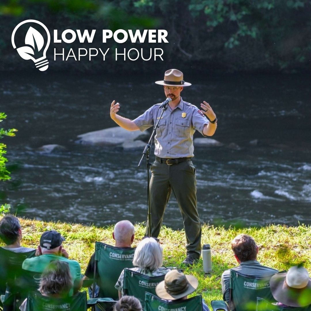Cuyahoga Valley National Park ranger Ryan Ainger speaks to a seated crowd by the Cuyahoga River.