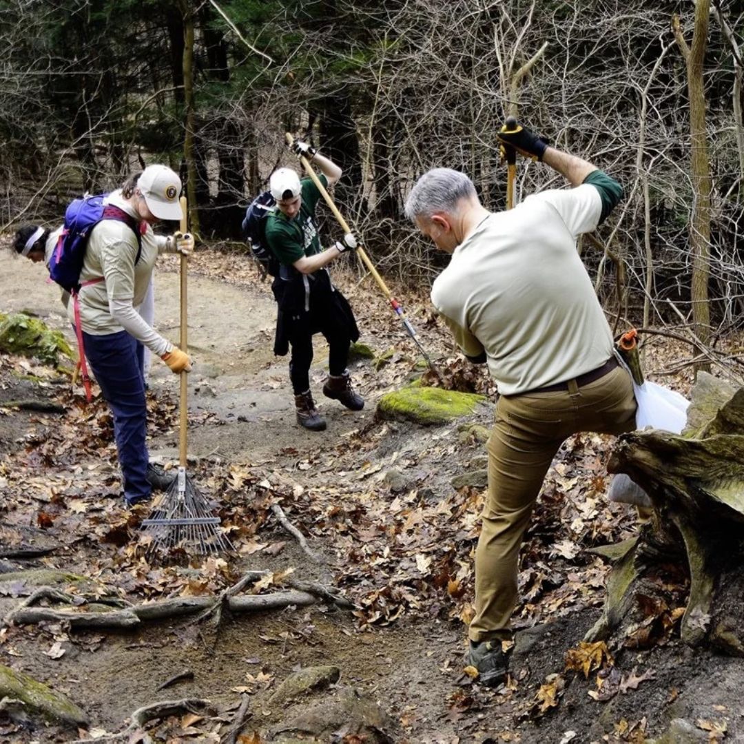 A photo of three people doing trail maintenance with yard tools for an Adopt a Trail event in CVNP.